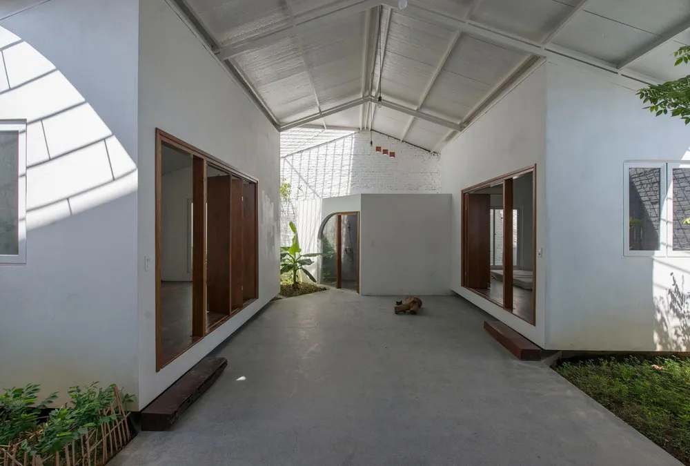 Bằng việc sử dụng màu trắng và ghi bao trùm các không gian, ngôi nhà như được mở rộng khi kết hợp với cây xanh.