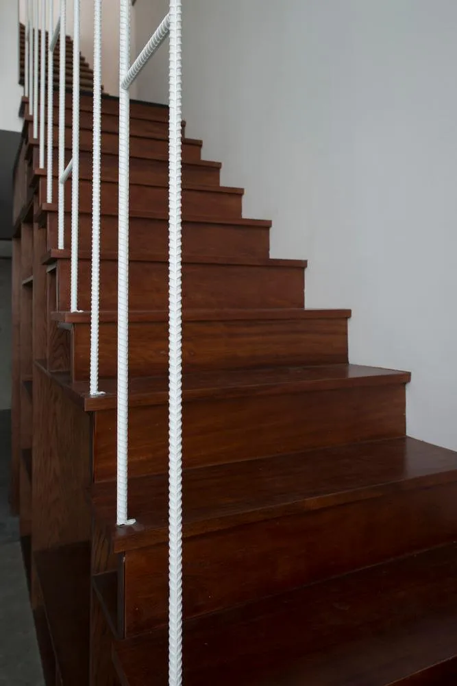 Cầu thang với lan can bằng sắt màu trắng nổi bật giữa nền cầu thang bằng gỗ.