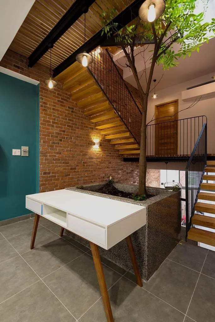 Bậc thang gỗ với kết cấu thép, hành lang trước phòng bằng lam gỗ. Kiến trúc sư sử dụng mảng gạch đỏ cho toàn bộ tường khu vực thông tầng.