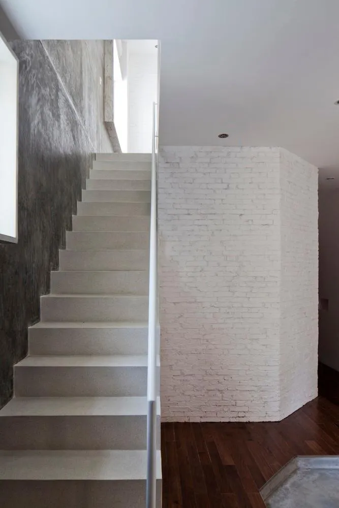 Chiếc cầu thang màu trắng nổi bật giữa không gian bên trong nhà.