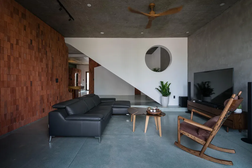 Tầng một bố trí kết nối các không gian mở, trải dài theo lớp sàn đá mài và một phòng ngủ với hướng nhìn ra khu vườn tĩnh sau nhà.