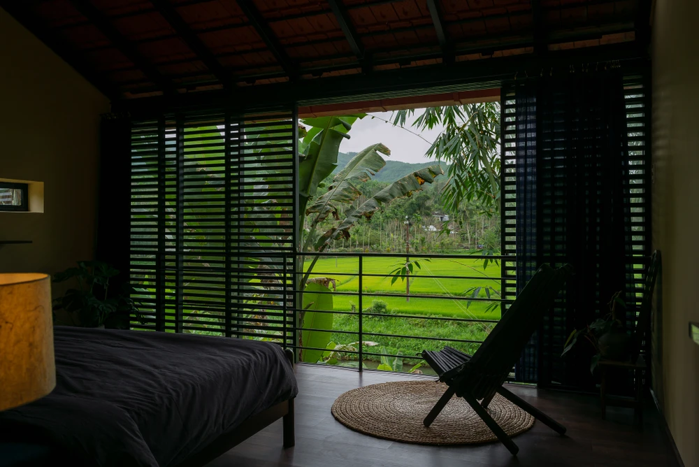 Phòng ngủ có view hướng ra khung cảnh của sườn núi đầy sương mù và đồng lúa.