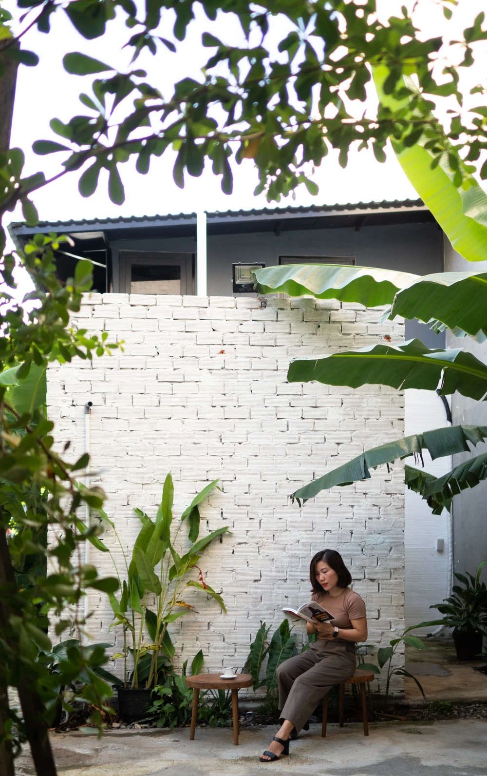 Khu vực vệ sinh được xây bằng gạch không tô sơn trắng, tạo sự mộc mạc. Nền sân tráng xi măng và rải đá, thoát nước tự nhiên vào các khu vực trồng cây.