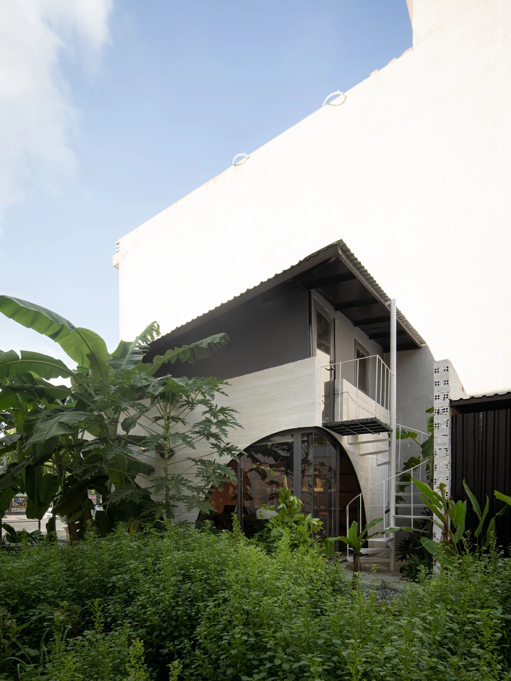 Không gian bao quanh ba mặt nhà là mảng xanh, cầu thang đi lên gác lửng đưa ra ngoài công trình để gần hơn với thiên nhiên.