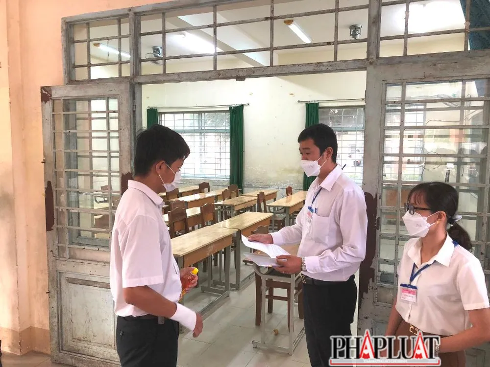 Cán bộ coi thi kiểm tra giấy báo thi của Hùng trước khi vào phòng. Ảnh: NHẪN NAM