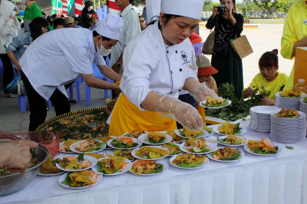 Bánh xèo khổng lồ được chia nhỏ thành 1.000 phần để mời người dân, du khách thưởng thức. Ảnh: NHẪN NAM banh-xeo-khong-lo-1.jpg