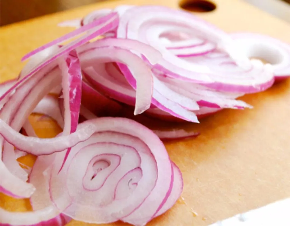 Nhai hành sống có thể giảm sưng lợi rất tốt.