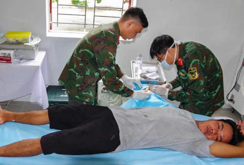 Quân y đang phẫu thuật vết cá chình cắn ở cổ tay cho ngư dân Doanh. Ảnh: NGUYỄN NINH ngư dân bị cá chình cắn khi đang đánh cá