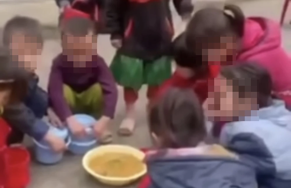 Các em học sinh ăn cơm giữa sân trường. Ảnh cắt từ clip