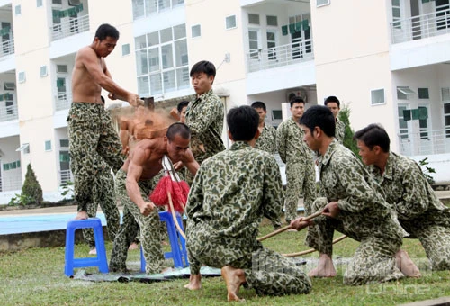 Mãn nhãn xem bộ đội Đặc công trình diễn võ thuật ảnh 15 Một chiến sĩ đặc công thể hiện khả năng phi thường, khi cổ họng ghì cong 3 cây đao nhọn, vai kê gạch để đồng đội công phá.