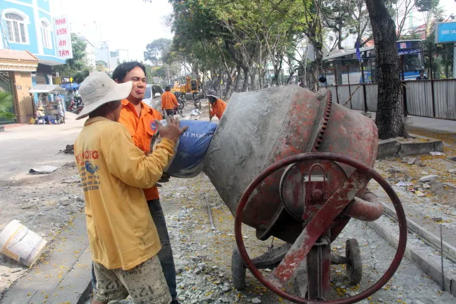 Công nhân đang đổ bê tông nền hạ trên vỉa hè đường Trần Quốc Hoàn sáng 19-1 - Ảnh: Quang Khải