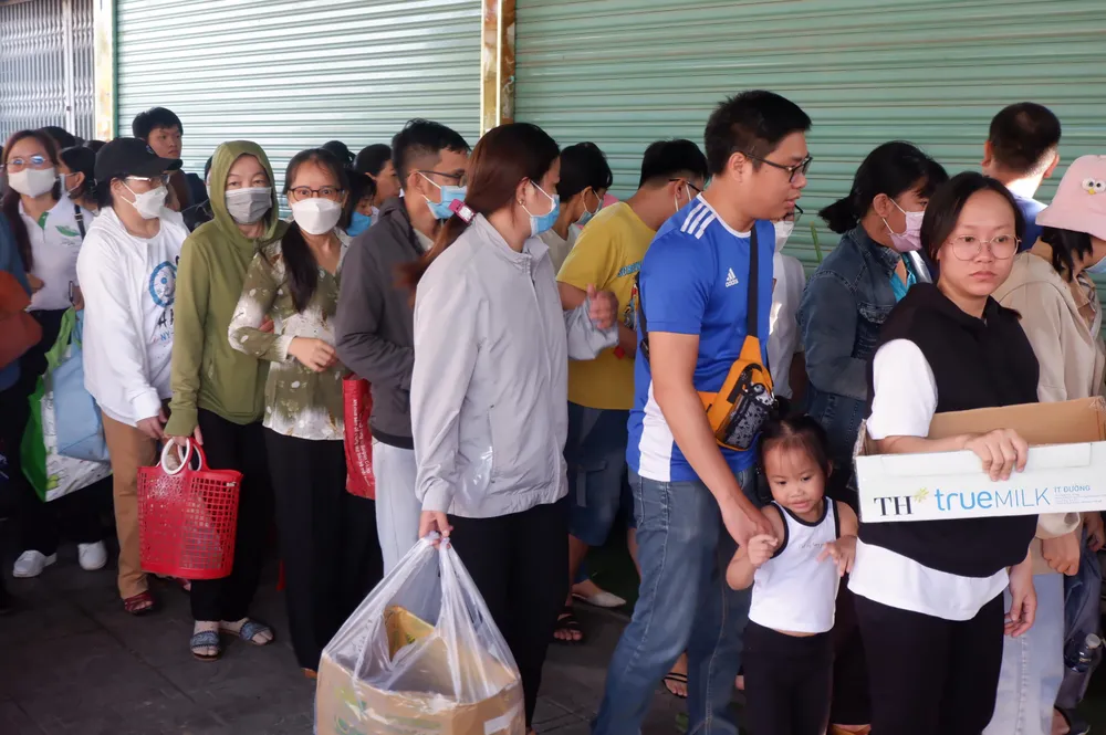 Nhiều người đem theo vỏ, túi vải đứng xếp hàng tham gia phiên chợ “0 đồng’ từ sáng sớm.