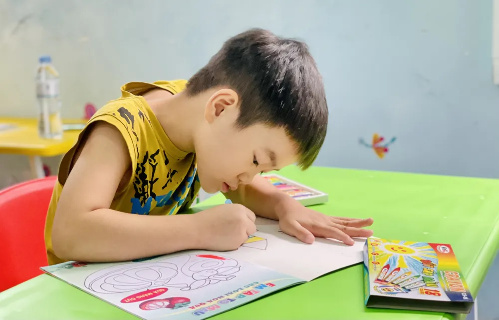 Con trai 5 tuổi của chị Trương Thị Dương chăm chú tô những bức tranh bé thích nhất. Ảnh: THẢO PHƯƠNG BV Nhi Dong 1.jpg