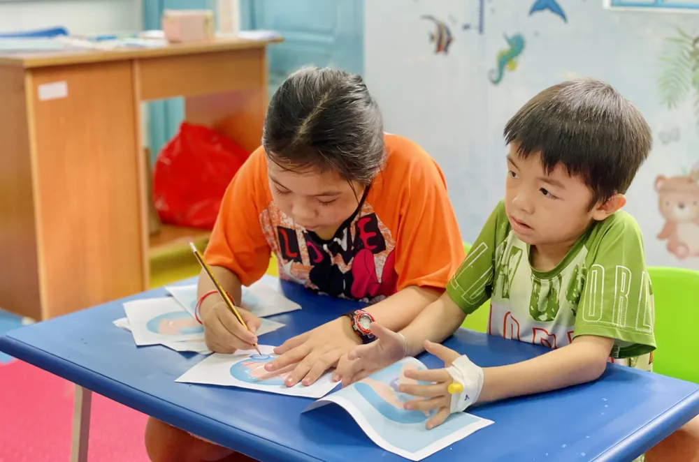 Các bệnh nhi chăm chú học hành dù trên tay còn dán kim truyền thuốc. Ảnh: THẢO PHƯƠNG lop hoc o BV Nhi Dong.jpg