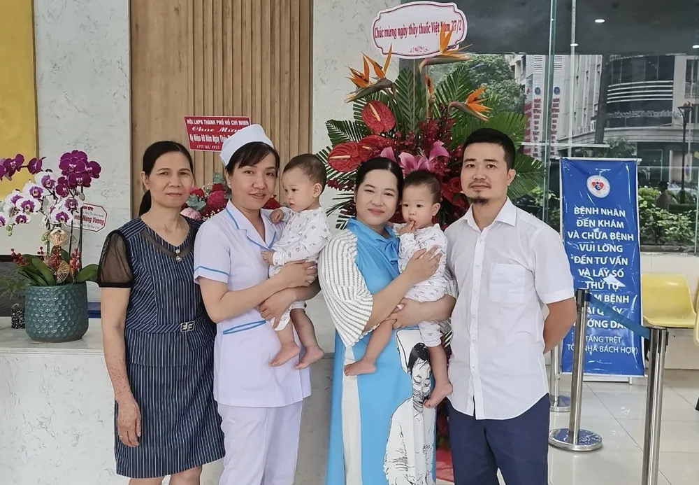 Gia đình chị Nguyễn Thùy Linh vui mừng gặp lại hộ sinh Phạm Thị Thùy Trang (thứ hai từ trái sang) tại BV Hùng Vương vào tháng 2-2023. Ảnh: NVCC y, bác sĩ