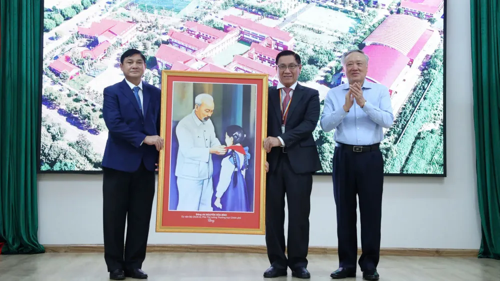 Phó Thủ tướng Thường trực Nguyễn Hòa Bình trao quà lưu niệm cho Trường Tiểu học, THCS và THPT Hoàng Việt. Ảnh: TD