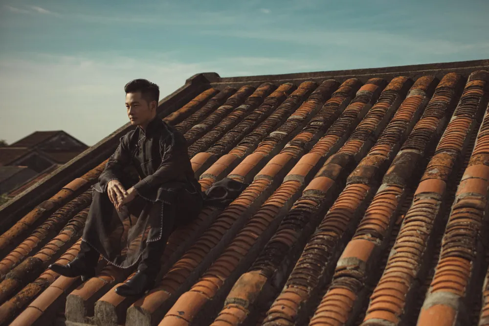 Ca sĩ Đức Tuấn đứng, ngồi trên nóc nhà cổ Hội An. Ảnh: Duc Tuan - the Divo. Ca sĩ Đức Tuấn đứng, ngồi trên nóc nhà cổ Hội An