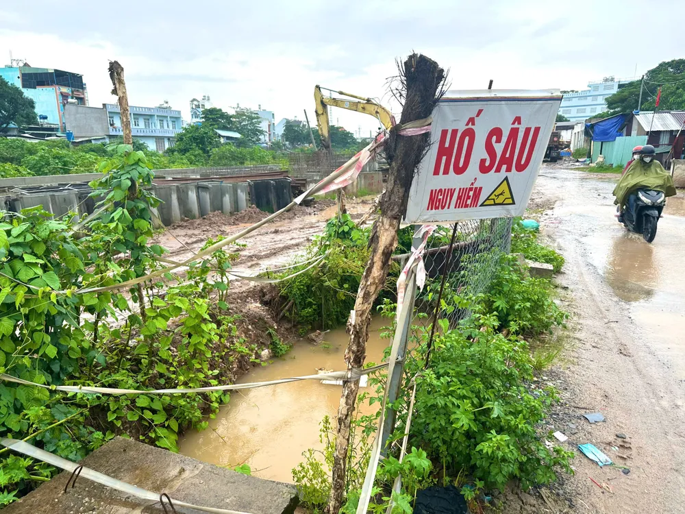 Một vài hố sâu khác chỉ được cắm sơ sài bằng một tấm biển “hố sâu nguy hiểm”, xung quanh dựng cành cây, cột một vài sợi dây cảnh báo cẩu thả. Ảnh: TH - TM buc-xuc-vi-nhieu-ho-sau-khong-co-rao-chan-truoc-truong-hoc.jpg