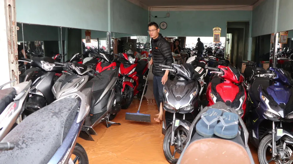 Nhân viên cửa hàng xe Thắng Lợi đang gấp rút dọn dẹp sau khi bị nước tràn vào. Ảnh CTV