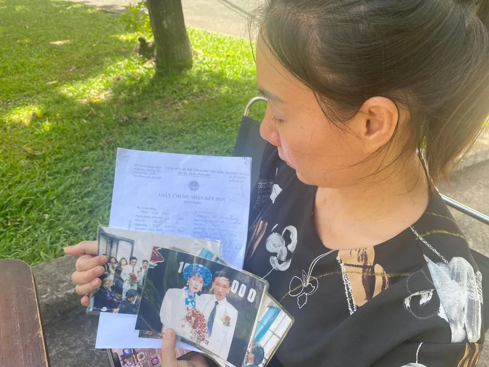 Bà Nguyễn Thị Kim Dung chia sẻ ảnh chụp tại lễ cưới của hai vợ chồng bà với phóng viên. Ảnh: HỮU ĐĂNG