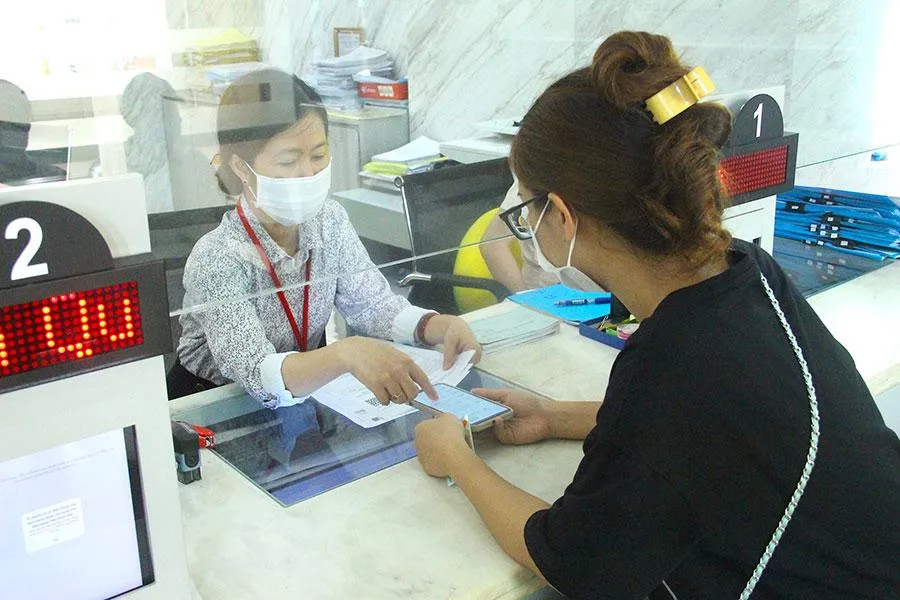 Cán bộ quận 1 hướng dẫn người dân làm thủ tục đăng ký kinh doanh trên mạng và sử dụng hệ thống định danh điện tử. Ảnh: LÊ THOA