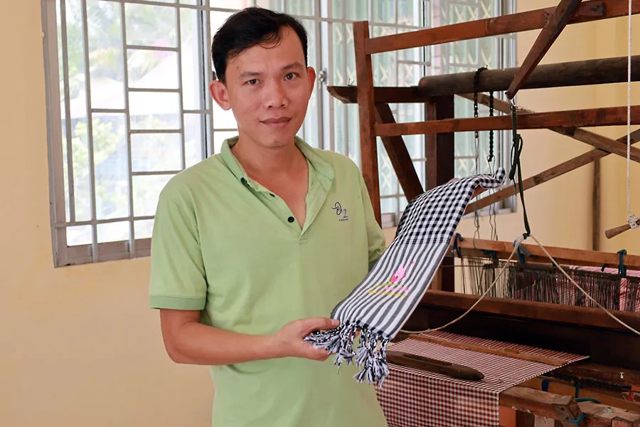 Anh Phạm Thanh An, Chủ nhiệm Hợp tác xã dệt choàng Long Khánh, cùng chiếc khăn rằn là sản phẩm của hợp tác xã. Ảnh: QUỐC HƯƠNG P13_niu-giu-cac-lang-nghe-bai-3.jpg