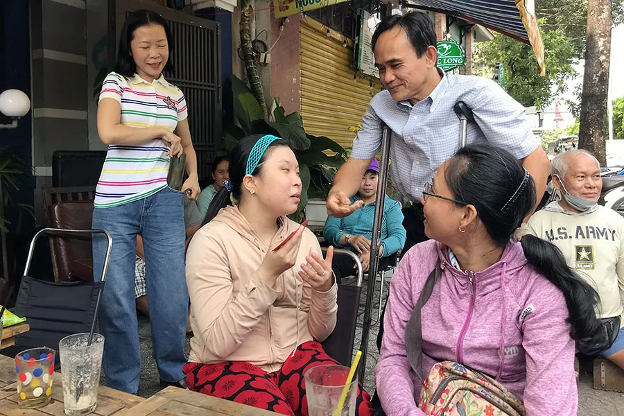 Chủ tịch Hội Thanh niên khuyết tật TP.HCM Võ Văn Anh (chống nạng) trò chuyện với các hội viên khuyết tật. Ảnh: VVA P13_nguoikhuyettat-hinhnho.jpg