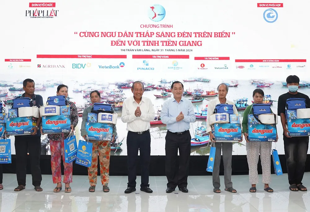 Ông Trương Hòa Bình, nguyên Ủy viên Bộ Chính trị, nguyên Phó Thủ tướng thường trực Chính phủ cùng ông Nguyễn Văn Vĩnh, Phó Bí thư Tỉnh ủy, Chủ tịch UBND tỉnh Tiền Giang trao quà cho ngư dân. Ảnh trong bài: HUỲNH DU - THUẬN VĂN Chương trình Thắp sáng đèn trên biển ở Tiền Giang