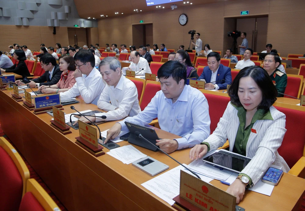 Các đại biểu HĐND TP Hà Nội bấm nút thông qua dự thảo Nghị quyết quy định việc áp dụng biện pháp yêu cầu ngừng cung cấp dịch vụ điện, nước đối với các công trình vi phạm về đất đai, trật tự xây dựng, phòng cháy chữa cháy trên địa bàn thành phố Hà Nội. Ảnh: TP