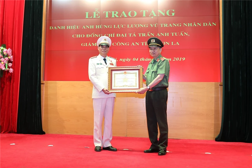 Bộ trưởng Tô Lâm gắn và trao danh hiệu Anh hùng Lực lượng vũ trang nhân dân tặng Đại tá Trần Anh Tuấn. Ảnh: Bộ Công an