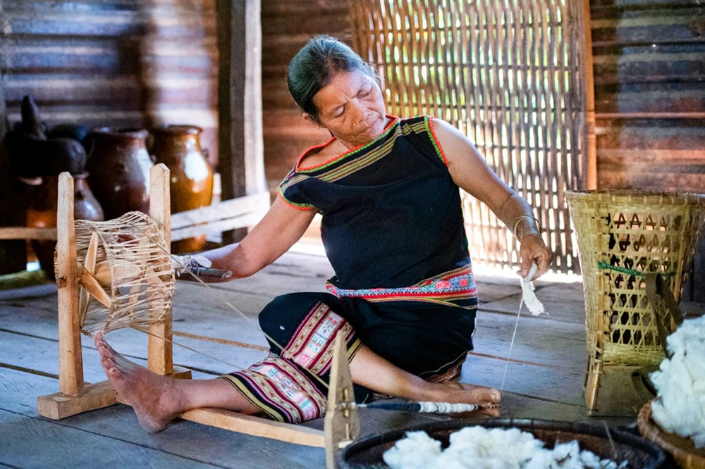 Nghệ nhân Y Yin (hơn 70 tuổi), kéo sợi bông bằng thủ công. Ảnh: HT.