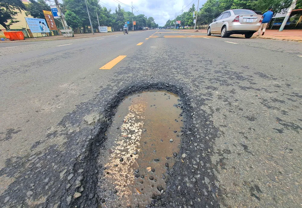 Mặt đường thảm nhựa bị bong tróc, lộ vạch kẻ đường cũ. Quoc-lo-19-hu-hong-2.jpg
