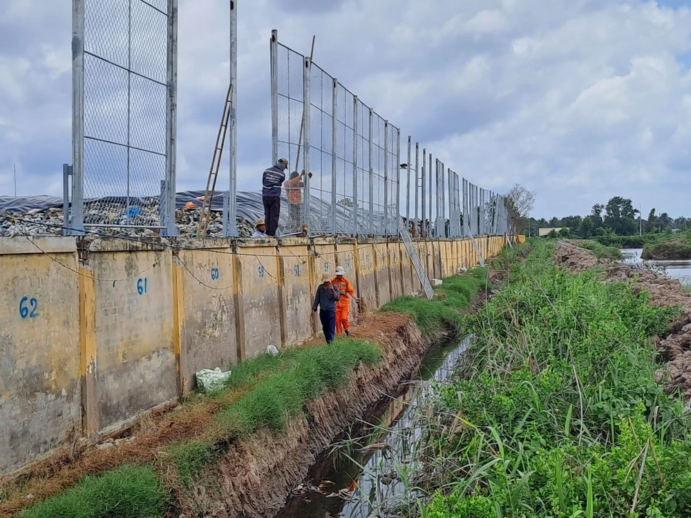 Đơn vị thi công khẩn trương dựng rào lưới cao 4m ngăn không cho rác thải bay qua hộ dân. ẢNH: ĐÔNG HÀ