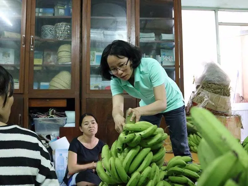 Các thành viên của Hội quán các bà mẹ đang bán, giao chuối cho người mua. 