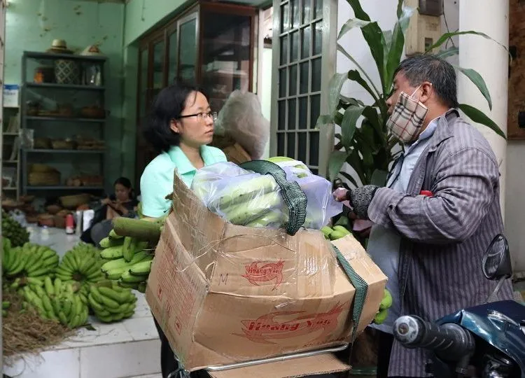 Thành viên của Hội quán các bà mẹ đang giúp khách hàng chở chuối về nhà. 