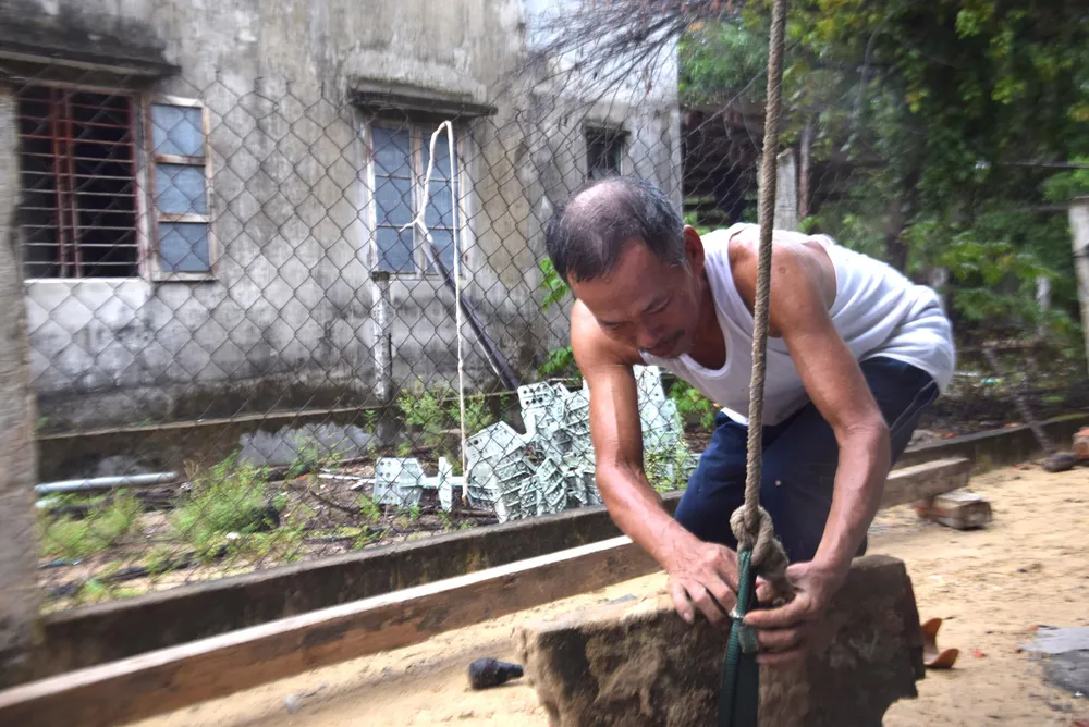 Từng tảng đá lớn được ông Lê Văn Văn (64 tuổi, ngụ thôn Thuận An) buộc vào dây. Ảnh: THANH NHẬT