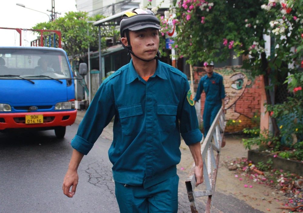 Lực lượng dân quân di chuyển thang đến nhà cần chằng chống.