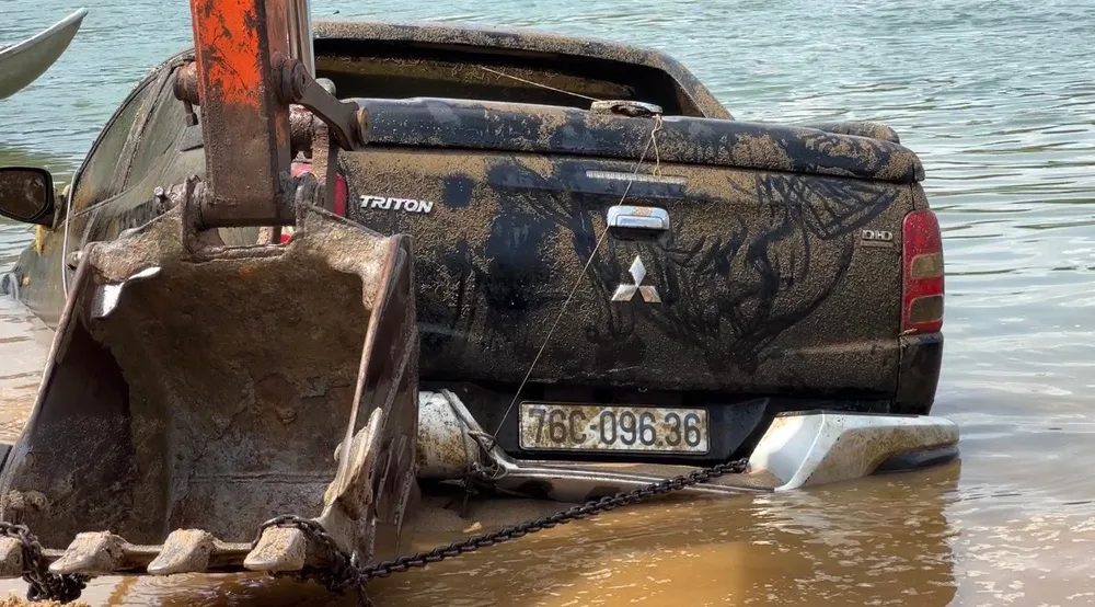 Chiếc ô tô được trục vớt lên bờ. Ảnh: CA