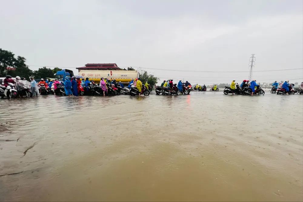 Nhiều công nhân lo trễ giờ làm phải dắt xe qua đoạn ngập nước. cong-nhan-mac-ket-vi-duong-ngap-3.jpg