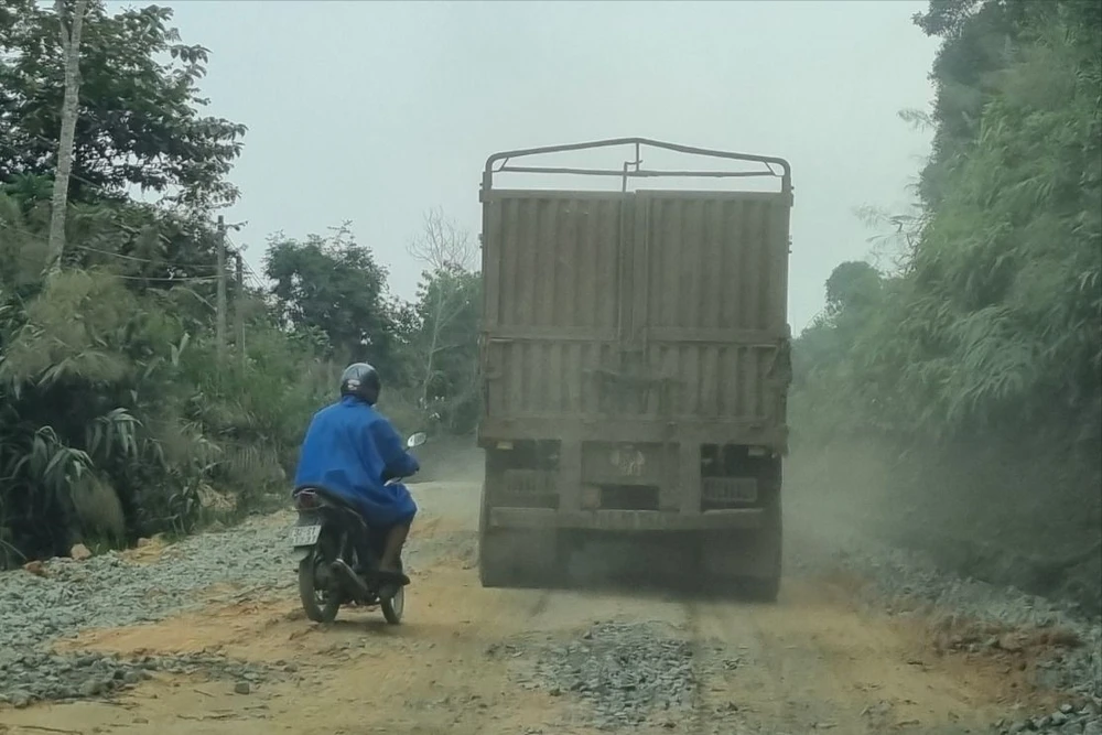 Người dân đi xe máy phải mặc áo mưa để bụi khỏi làm bẩn áo dù thời tiết đang nắng nóng. Ảnh: TN quoc-lo-14D-tan-nat-5.jpeg