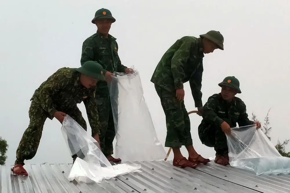 Đồn Biên phòng Bình Minh giúp người dân chằng chống nhà cửa. Ảnh: HA bo-doi-giup-dan-chang-nha-chong-bao-Tra-mi-9.jpeg