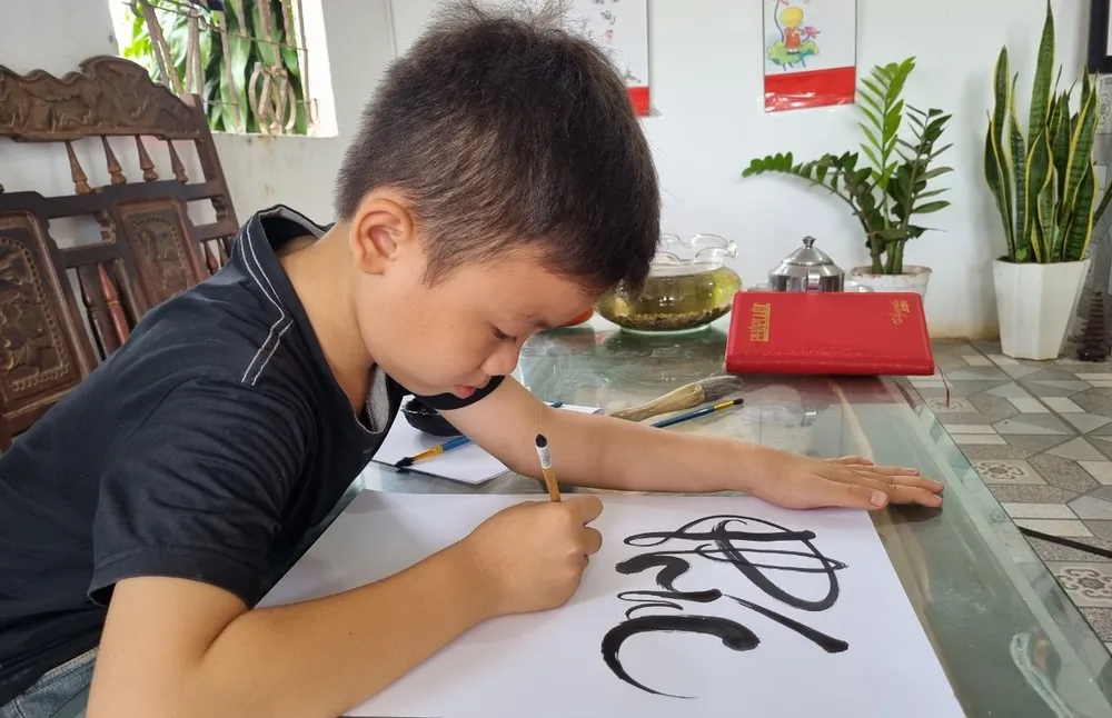 Cháu Nghĩa thể hiện khả năng viết thư pháp. Ảnh: TIẾN THOẠI vẽ tranh 2.jpg