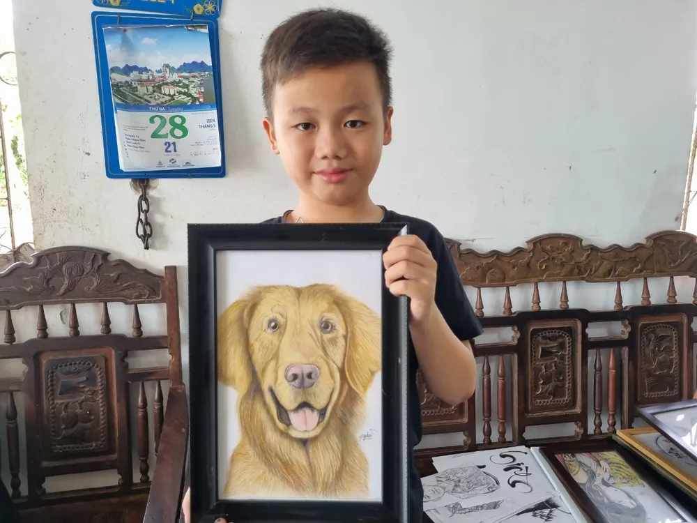 Cháu Nghĩa khoe bức tranh vẽ chú chó giống như thật. Ảnh: TIẾN THOẠI vẽ tranh 3.jpg