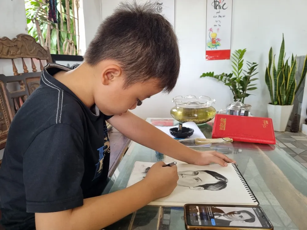 Cháu Nghĩa vẽ chân dung Chủ tịch Hồ Chí Minh thời trẻ. Ảnh: TIẾN THOẠI vẽ tranh 7.jpg
