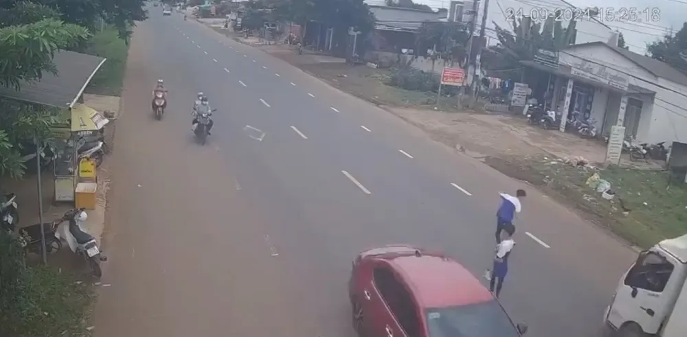 Em Trí (góc phải) chạy né ô tô và bị xe tải tông trúng. Ảnh: Chụp màn hình né ô tô.jpg