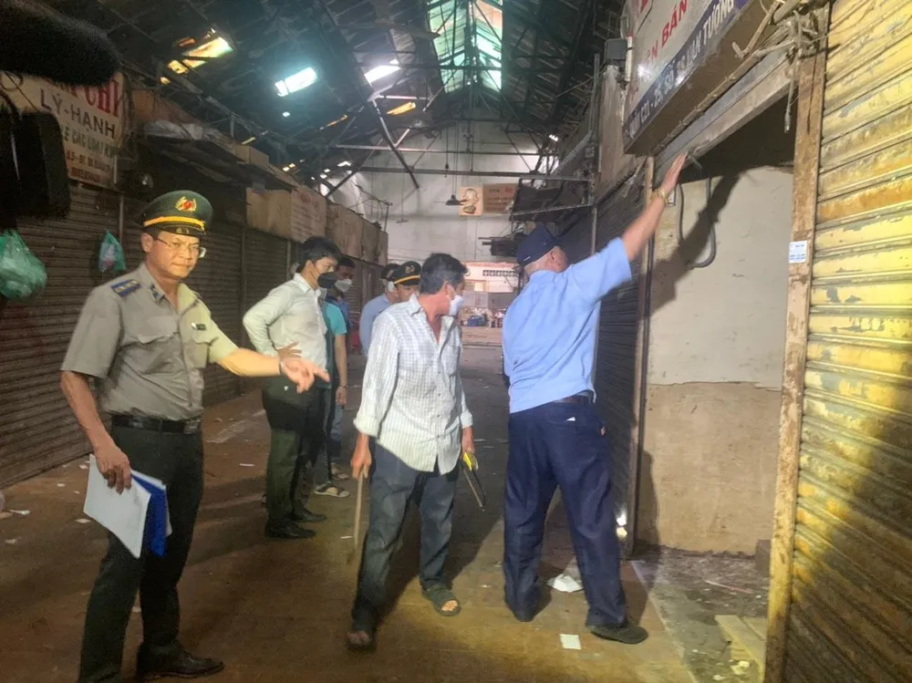 Đoàn cưỡng chế tiến hành mở khóa các sạp chợ, kiểm đếm tài sản chưa di dời. Ảnh: TRÚC PHƯƠNG