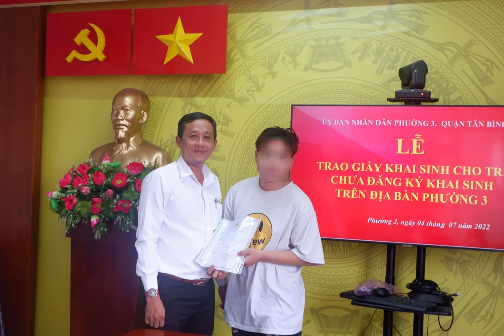 Ông Võ Tấn Tài, Phó Chủ tịch UBND phường 3 (quận Tân Bình) trao giấy khai sinh cho H. Ảnh: TRÚC PHƯƠNG