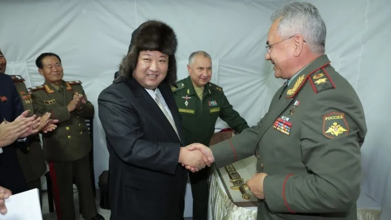 Ông Kim Jong-un (trái) đội chiếc mũ lông ushanka do Bộ trưởng Quốc phòng Nga Sergey Shoigu (phải) tặng. Ảnh: RT nga-150-5901.jpg
