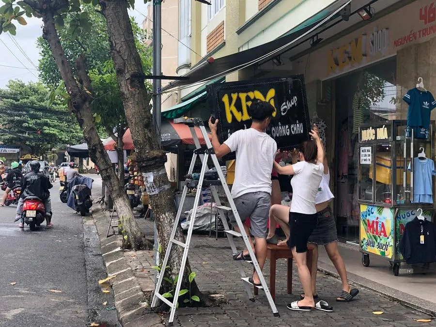 Người dân hạ các biển quảng cáo để đảm bảo an toàn. Ảnh: NGÔ QUANG