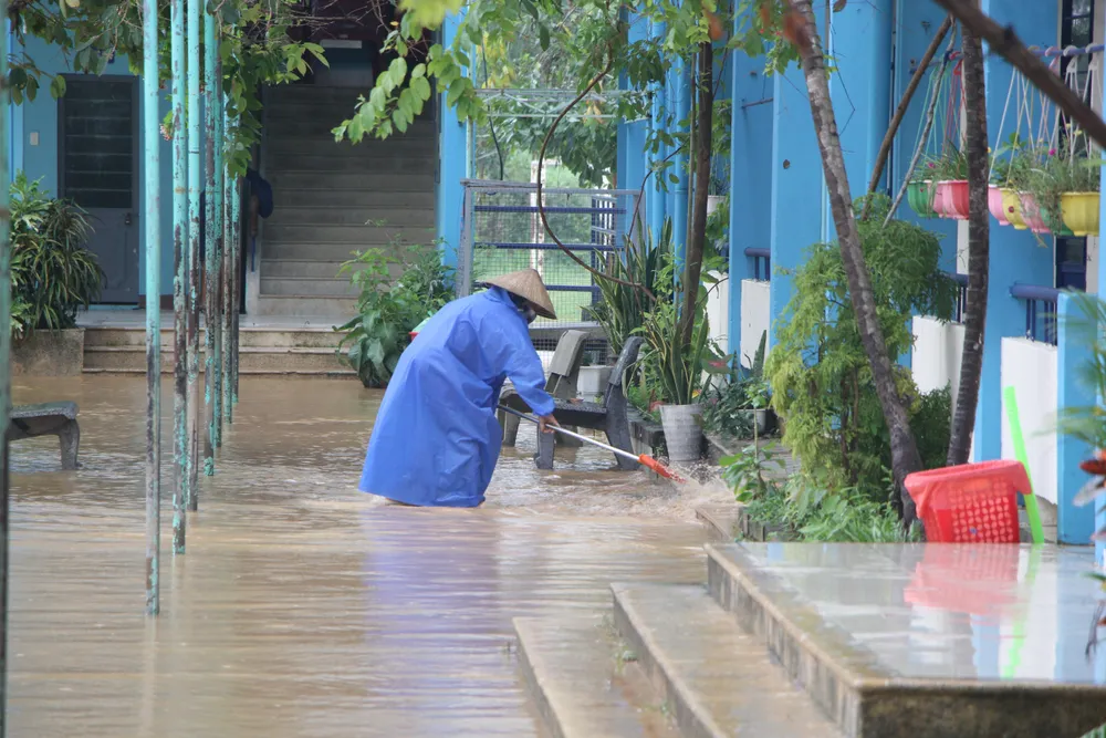 Người dân xung quanh trường phụ giúp tạt bớt nước. Ảnh: NGÔ QUANG